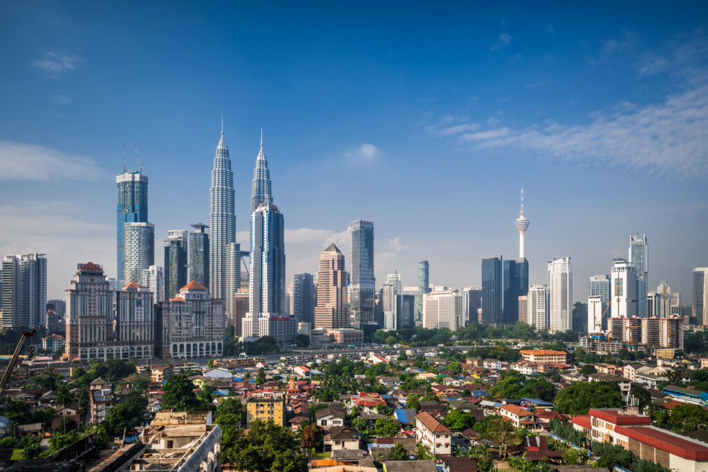 Zicht op de moderne skyline van Kuala Lumpur, Maleisië, met de iconische Petronas Twin Towers en de KL Tower die boven de stad uitsteken.