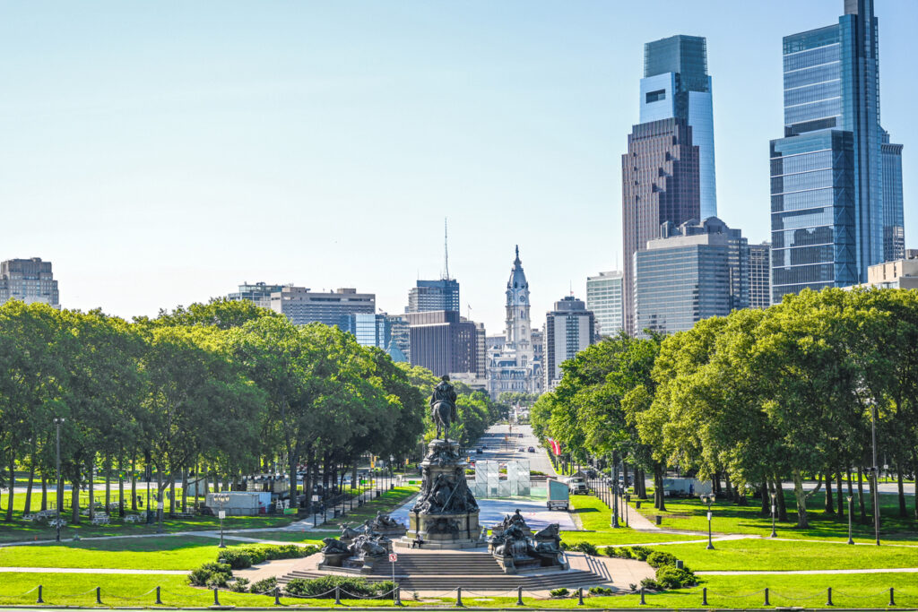 Een stadsgezicht in vogelvlucht op de Benjamin Franklin Parkway in Philadelphia, met het ruiterstandbeeld van het Washington Monument omringd door bomen en wolkenkrabbers.