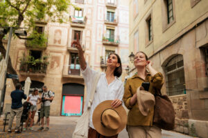 Two female friends look up at the surrounding architecture as one points toward a building while sightseeing in a historic city neighborhood © iStock - miodragignjatovic